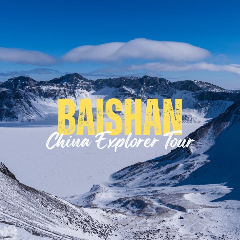 Baishan,Jilin Province,China tour Snowy mountain landscape with blue sky and a large yellow 'BAISHAN' title and white cursive 'China Explorer Tour' text overlayed.