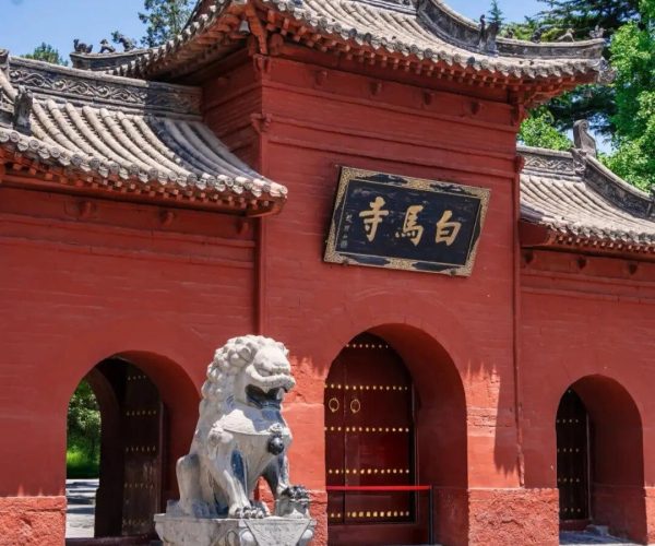 White Horse Temple,Luoyang,Chinatravel Traditional Chinese temple gate with red walls, ornate tiled roof, and a stone guardian lion in the courtyard.