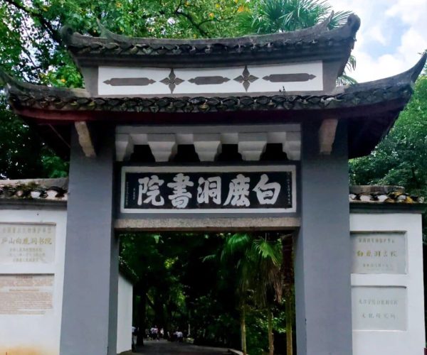 White Deer Cave Academy,Jiujiang,China tour Entrance to a Chinese-style garden or temple with a curved tiled roof and a black plaque bearing white Chinese characters above the doorway.