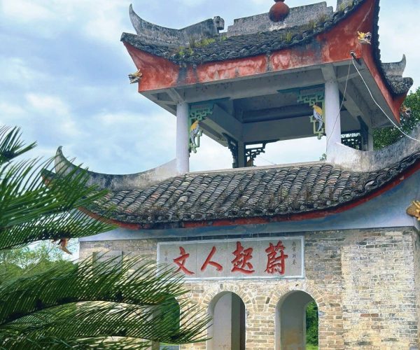 Fuli Ancient Town,Yangshuo,Chinatravel Brick Chinese-style gate with a tiled, upturned roof, and a plaque with red Chinese characters; arched openings in the wall behind.