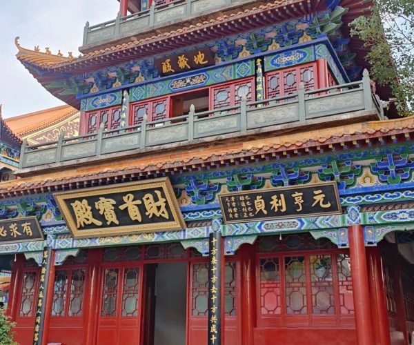Zhanghua Temple,Jingzhou,Chinatravel ornate multi-tier Chinese temple facade with blue, red, and gold detailing; Chinese signage panels on each level.