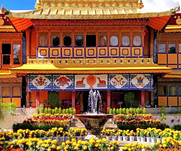 Norbulingka Park,Lhasa,Chinatravel Ornate golden temple facade with blue sky, surrounded by a colorful flower garden and a central fountain.