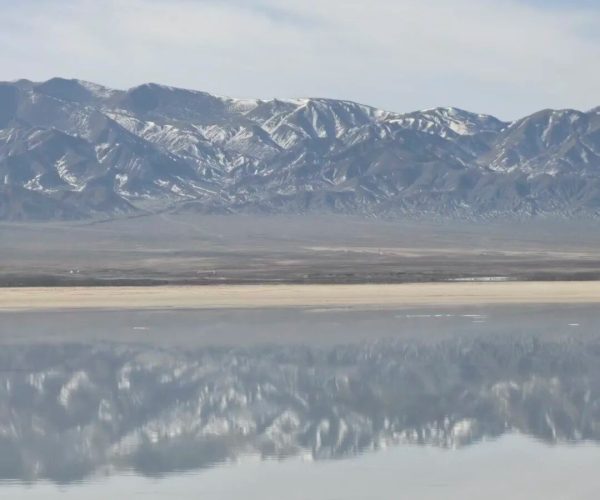 Chaka Salt Lake,Xining,Chinatrip Snow-capped mountain range reflected in a calm body of water under a blue sky.