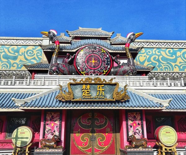Jingzhou Fantawild Adventure,Jingzhou,Chinatravel Front view of a colorful Chinese palace entrance with dragon statues, ornate red doors, and a bright blue sky above.