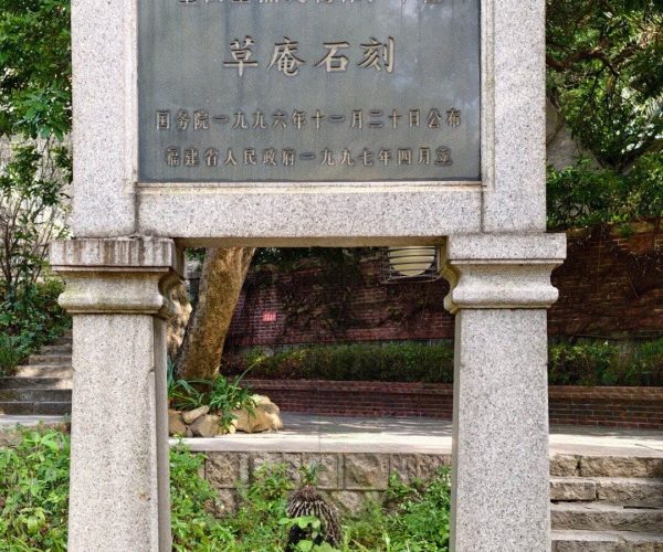Grass Hut Manichaeism Site,Quanzhou,Chinatravel Stone sign with a Chinese inscription framed by two granite pillars in a garden.