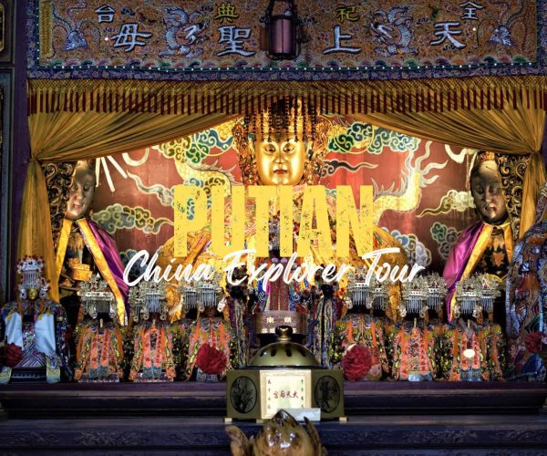 Putian,Fujian,Chinatravel Golden Buddha statue in a richly decorated shrine, flanked by smaller elaborately dressed figures and ceremonial objects, with bold yellow overlay text reading 'Pilan China Explorer Tour' across the front.