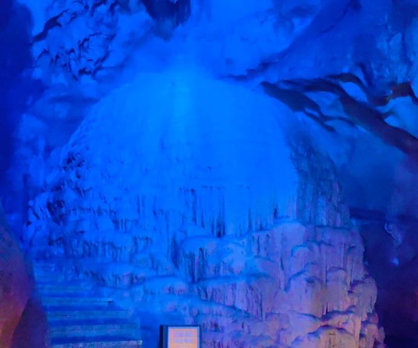 Penglai Fairy Cave,Chizhou,China tour Blue-lit cave interior with stepped staircase along rock walls and a lit sign at the base.