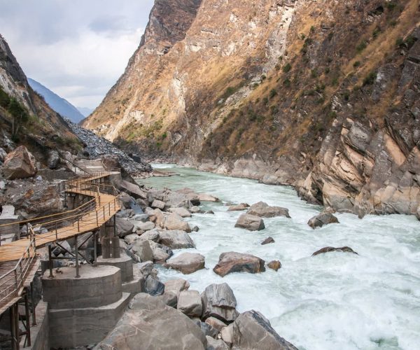 Tiger Leaping Gorge,Lijiang,Chinatravel Wooden walkway with railings along a rocky canyon beside a fast-flowing river.