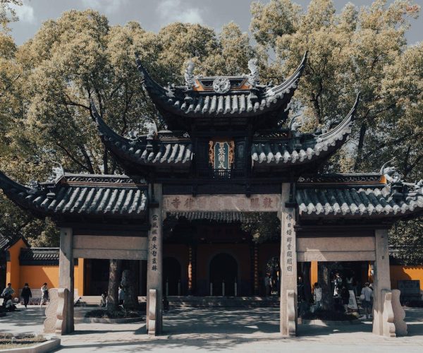 Xiyuan Temple,Suzhou,Chinatravel Traditional Chinese temple gate with curved tiled roofs and stone pillars, surrounded by trees and visitors