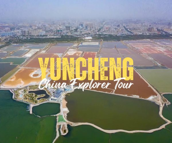 Yuncheng,Shanxi,Chinatravel Aerial view of Yuncheng city with colorful salt evaporation ponds in the foreground and a city skyline in the distance, overlaid with bold yellow text 'YUNCHENG' and white script 'China Explorer Tour'
