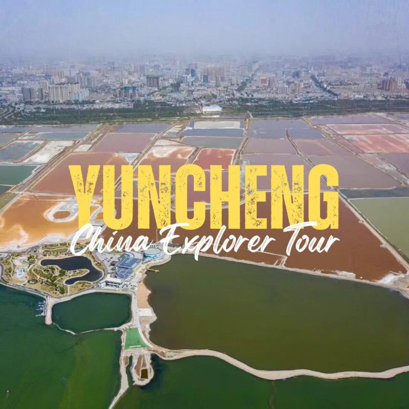 Yuncheng,Shanxi,Chinatravel Aerial view of Yuncheng city with colorful salt evaporation ponds in the foreground and a city skyline in the distance, overlaid with bold yellow text 'YUNCHENG' and white script 'China Explorer Tour'