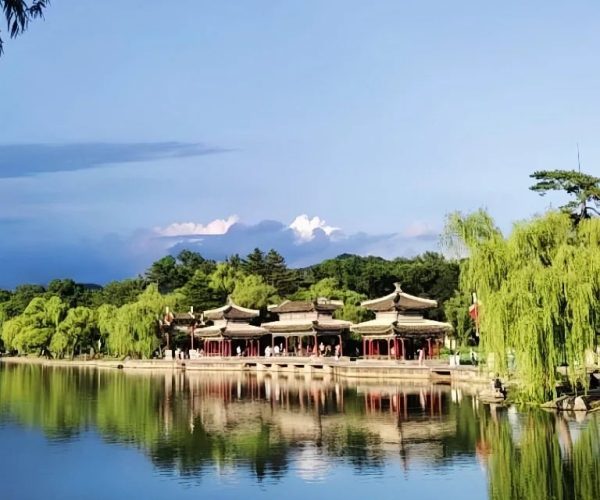 Chengde Mountain Resort,Chengde,China tour Blue sky over a tranquil lake with traditional Chinese pavilions reflected on the water, surrounded by weeping willows and greenery.