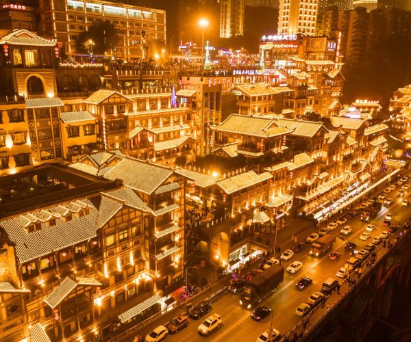 Hongya cave, chongqing, chinatravel, Nighttime aerial view of a busy street lined with illuminated traditional Chinese buildings and glowing rooftops in a Chinatown district.
