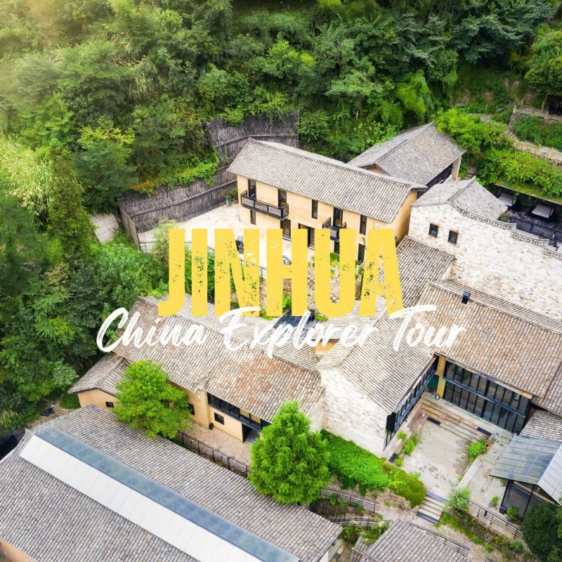Jinhua,Zhejiang,Chinatravel Aerial view of a traditional Chinese village with tiled roofs and lush green hills, overlaid by bold yellow 'JINHUA' and white script text.