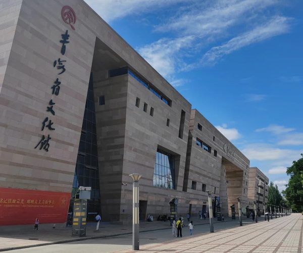 Qinghai Provincial Museum,Xining,Chinatrip Modern cultural center with tall stone walls, large Chinese characters on the left, and a wide tiled plaza under a blue sky.