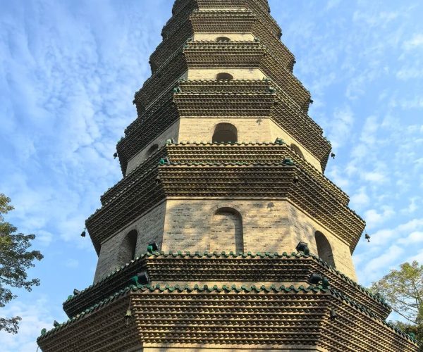 Qingxiu Mountain Ancient Pagoda,Nanning,Chinatravel Tall multi-tiered brick pagoda with upturned green-tiled eaves against a blue sky.