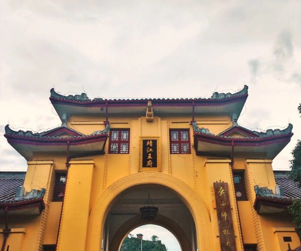 Jingjiang Princes’ City,Guilin,Chinatravel Yellow Chinese-style gate with ornate green-tiled roof and a large central arch, visitors entering a courtyard beyond.