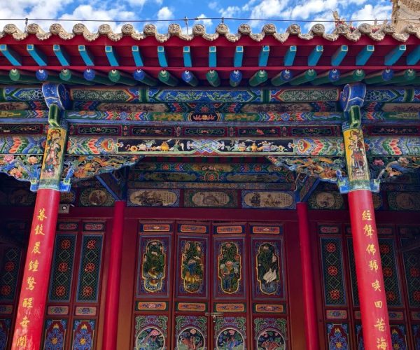 Gao Temple,Zhongwei,China tour Colorful Chinese temple facade with red pillars, ornate painted beams, and decorative doors under a bright blue sky.