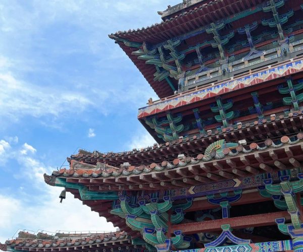 Stork Tower,Yuncheng,Chinatravel Multi-tiered ornate Chinese temple roof with blue, green, and red decorations against a blue sky; a red lantern hangs in the foreground.