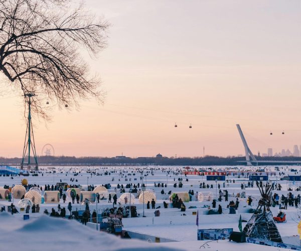 Heilongjiang Weather,Heilongjiang,Chinatravel Wide snowy park crowded with people, cable cars gliding across the sky, and a distant city skyline at sunsetlightened by pastel skies.