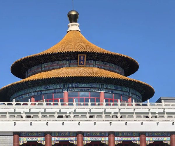 Dacheng Temple,Qiqihar,Chinatravel Round, orange-tiled, circular temple roof with ornate blue-green trim atop a brick building with red columns, set against a clear blue sky.