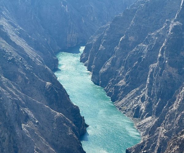 Longyangxia Reservoir & Canyon,Hainan Prefecture,China tour Turquoise river snakes through a steep rocky canyon with towering gray cliffs.