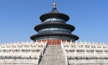 Temple of Heaven, Beijing, Chinatrip, Circular, multi-tiered Chinese temple with blue-green ceramic tiles and gold accents, perched on a stone stairway with a white railing under a clear blue sky.