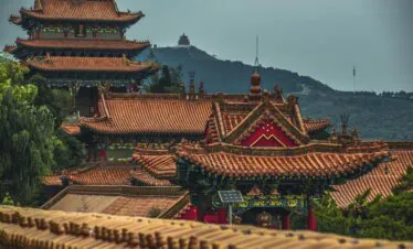 Chongqing Huguang Guild Hall, China Travel, Traditional Chinese temple complex with red tiled roofs and ornate carvings, set against a hilly landscape.