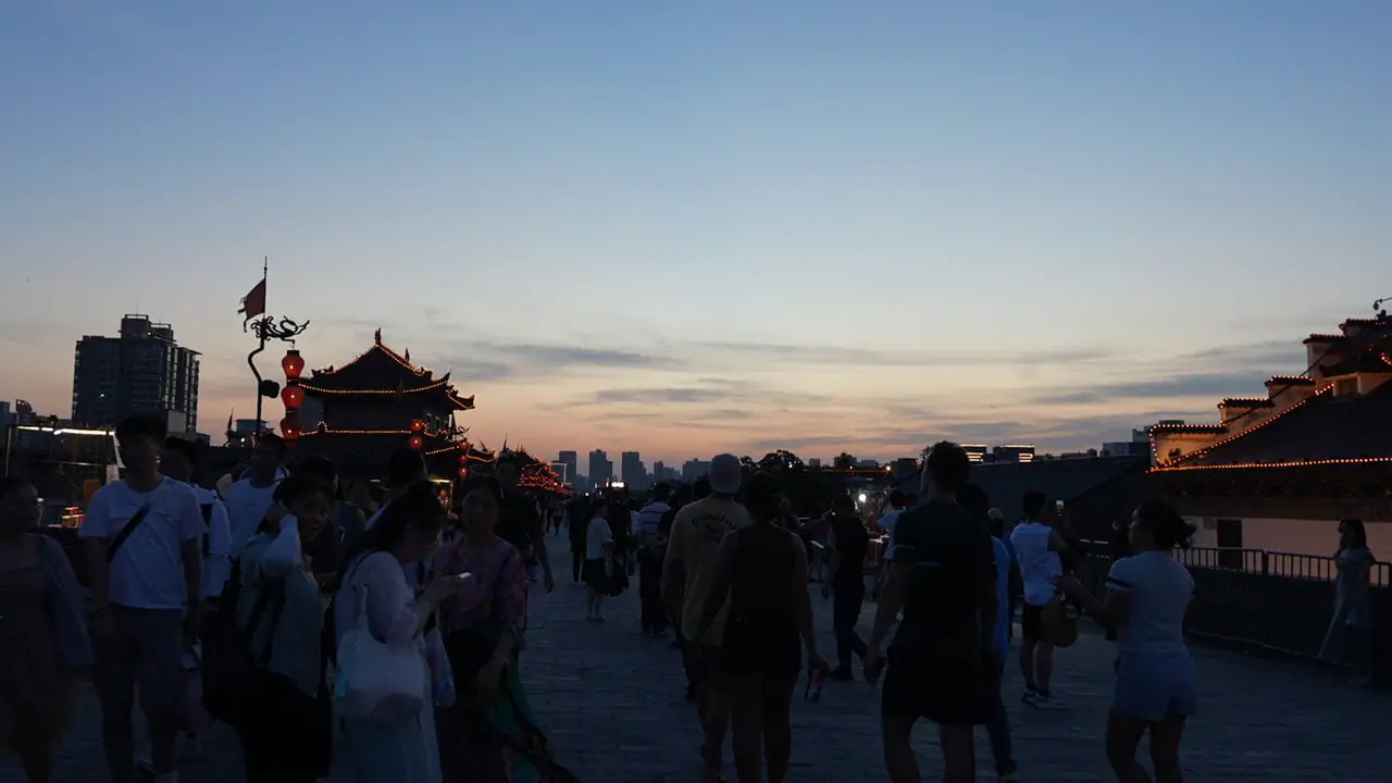 xi'an, china, china tour, Crowd of people strolling on a sunset-lit festival street with a Chinese pagoda and lanterns along the buildings.