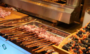 chinese cuisine, xi'an, china, china tour, Skewers of raw meat on a grill at a street food stall with a stainless steel hood nearby.