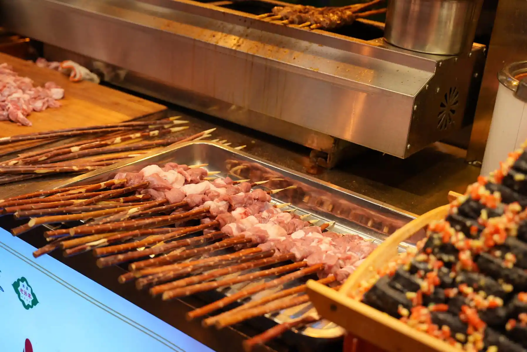 chinese cuisine, xi'an, china, china tour, Skewers of raw meat on a grill at a street food stall with a stainless steel hood nearby.