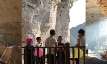 14-Day China Cultural Odyssey: From Iconic Landmarks to Hidden Gems, china, china tour, Group of people chatting near a wooden railing inside a spacious cave with row of tents and balloons nearby.
