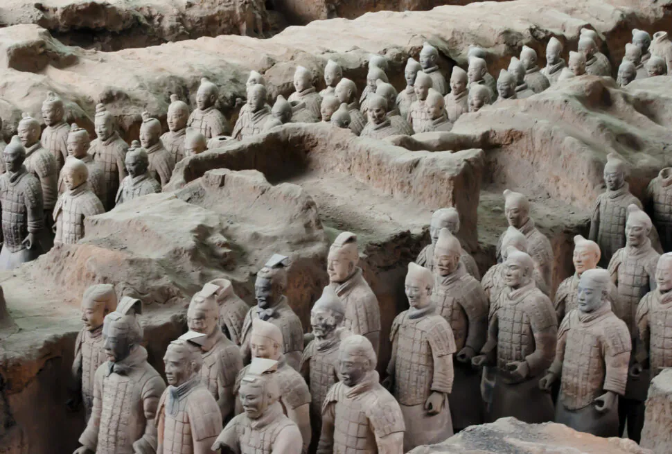 Terracotta Warriors Museum in Xi'an, Chinatravel, Rows of life-size terracotta soldiers wearing armor, standing in sunlit earthen pits as part of a tomb army excavation site.