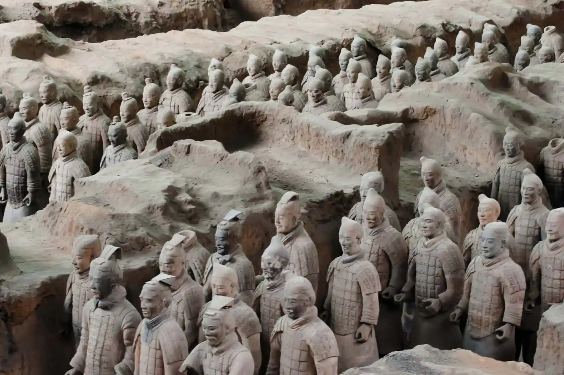 Terracotta Warriors Museum in Xi'an, Chinatravel, Rows of life-size terracotta soldiers wearing armor, standing in sunlit earthen pits as part of a tomb army excavation site.