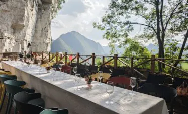 5-Day Hidden Gem - Guizhou Retreat: Caves, Culture, and Culinary Delights, china, china tour, Outdoor mountain-view dining setup with a long table, wine glasses, and pastel chairs on a balcony.