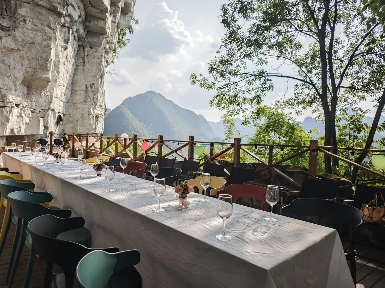 5-Day Hidden Gem - Guizhou Retreat: Caves, Culture, and Culinary Delights, china, china tour, Outdoor mountain-view dining setup with a long table, wine glasses, and pastel chairs on a balcony.