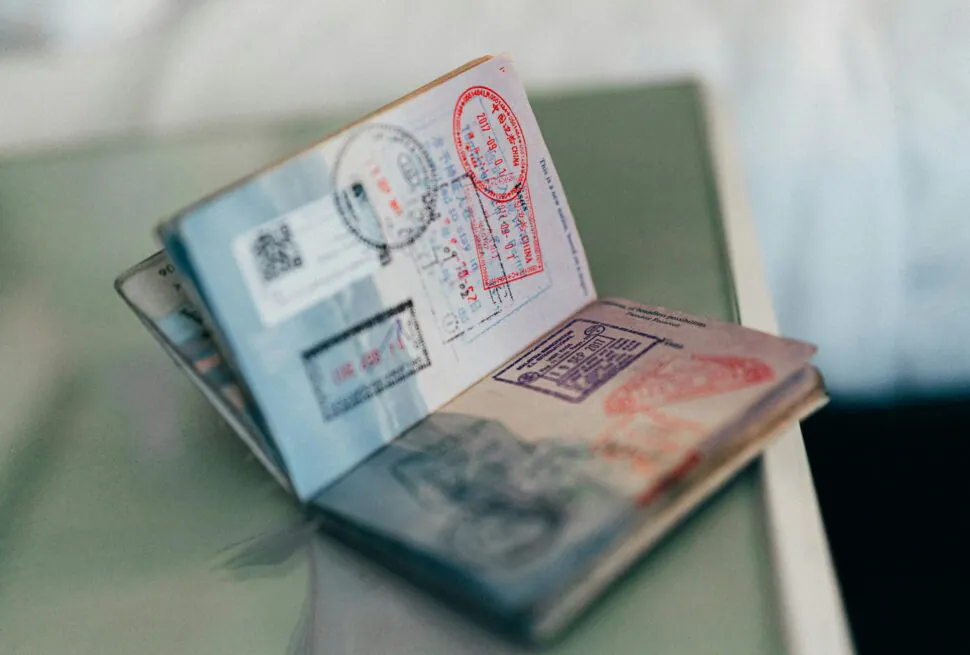 China Travel Guide 2025: Visa, Transportation, Itineraries and More, chinaexplorertour, Close-up of stacked passports with red and blue visa stamps visible on the pages, resting on a surface.