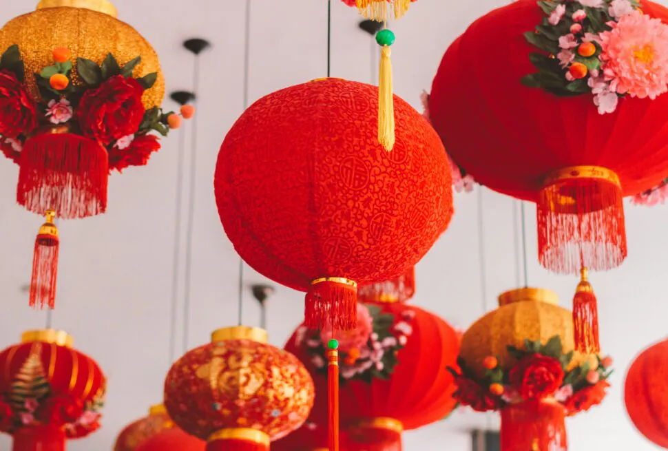 Discover the Magic of Chinese New Year 2025, chinaexplorertour, Red Chinese lanterns with gold tassels and floral arrangements hanging indoors, festive decoration.