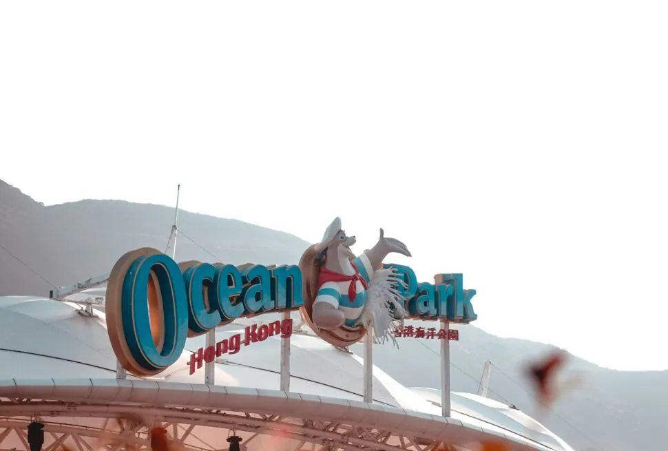 ocean park, hong kong, china, chinaexplorertour, Ocean Park Hong Kong entrance sign with large blue letters and mascot statue against a mountain backdrop.