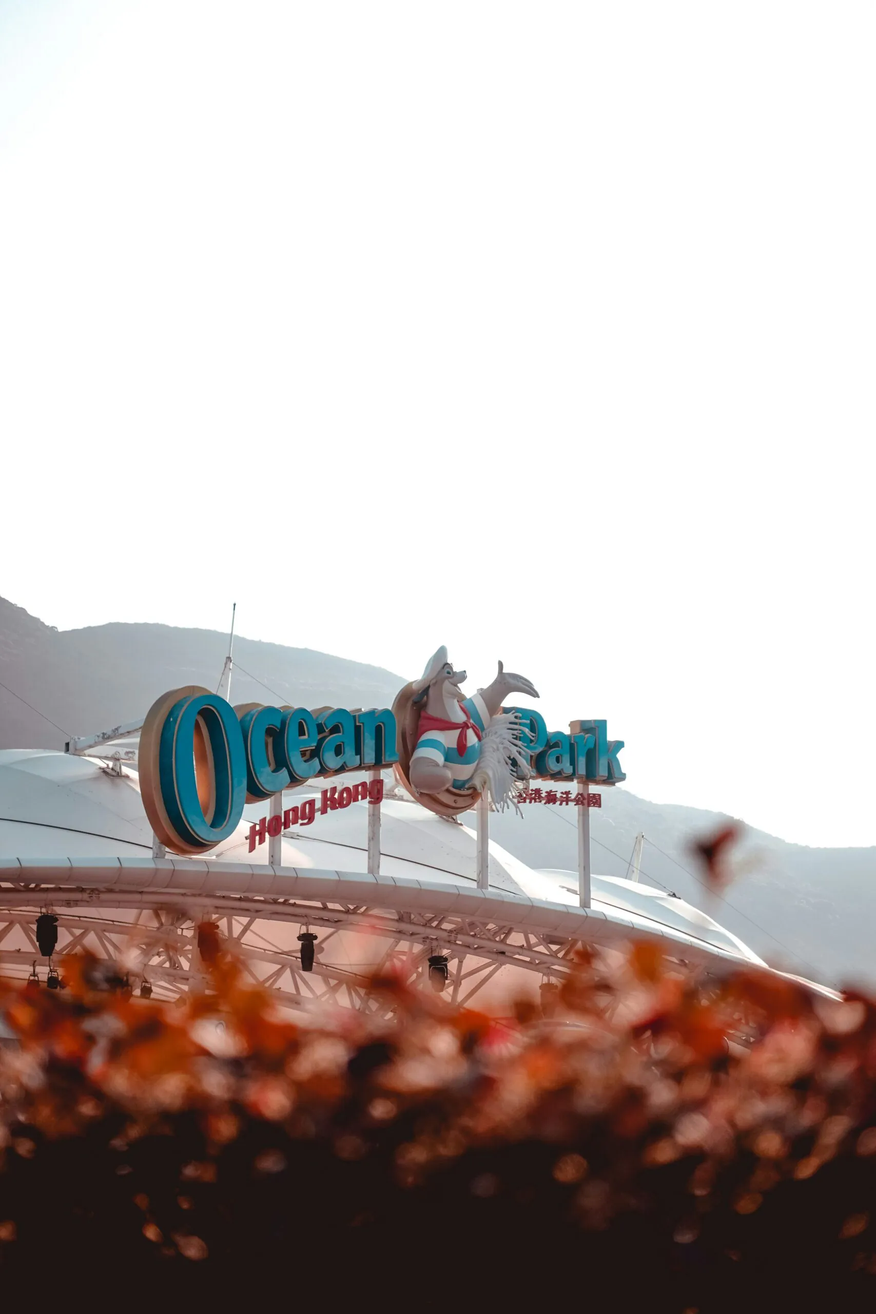 ocean park, hong kong, china, chinaexplorertour, Ocean Park Hong Kong entrance sign with large blue letters and mascot statue against a mountain backdrop.
