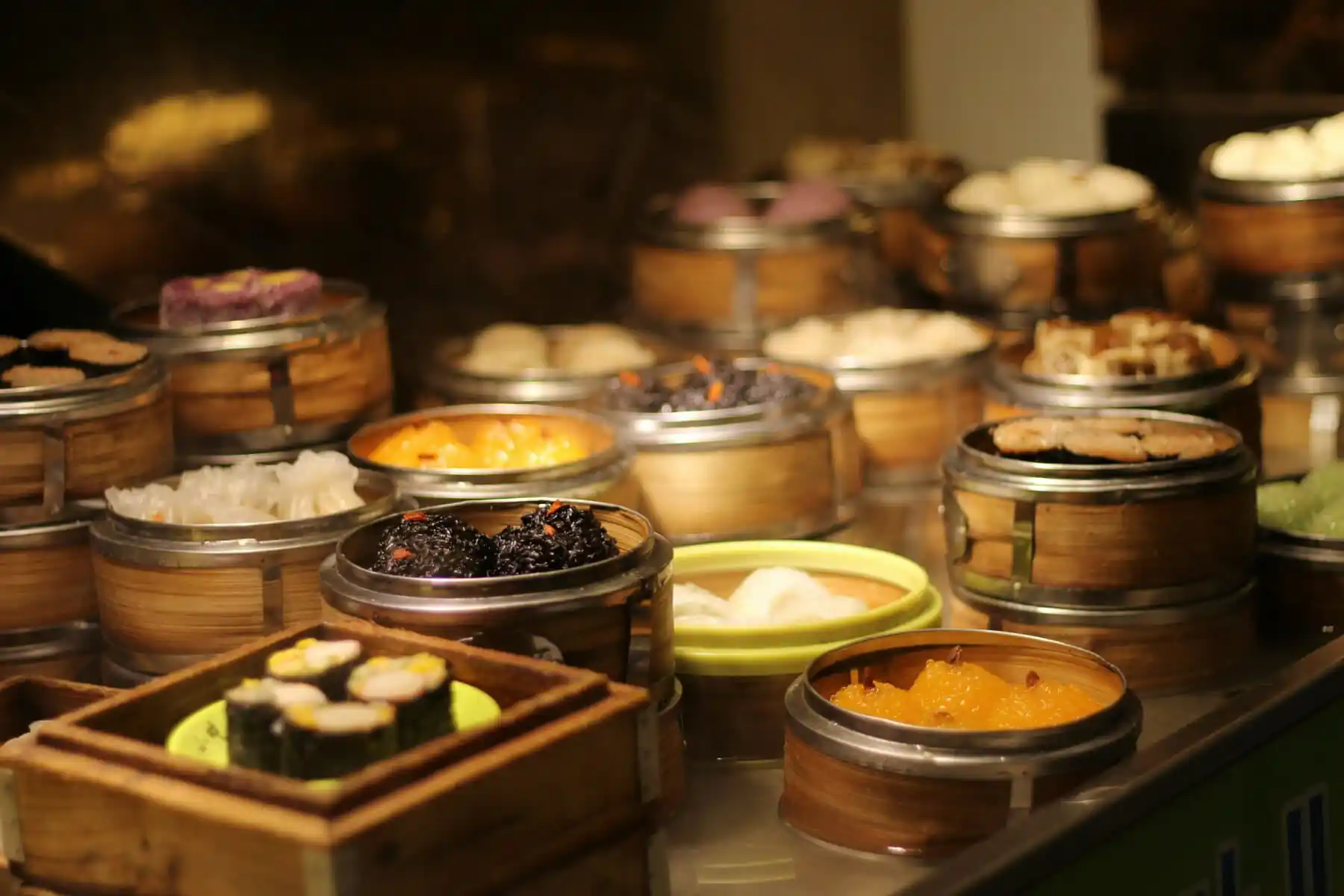 Dim Sum, Cantonese food, Chinese Food, chinatravel, Assorted dim sum in bamboo steamers on a market counter, warm lighting highlighting the steamer baskets.