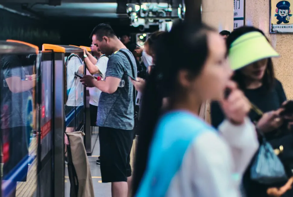 chinese subway, chinatravel, Commuters wait on a subway platform beside a blue train, some looking at phones; a masked woman in the crowd is visible.