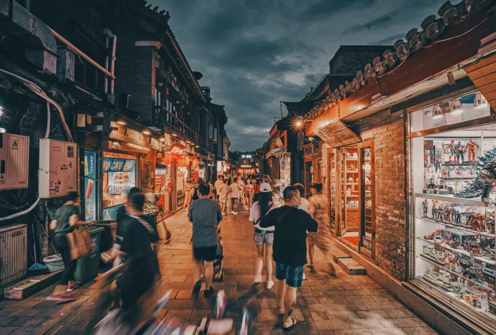 Bustling night market street lined with shops and Beijing hutong, chinatravel, illuminated displays, people walking and browsing.