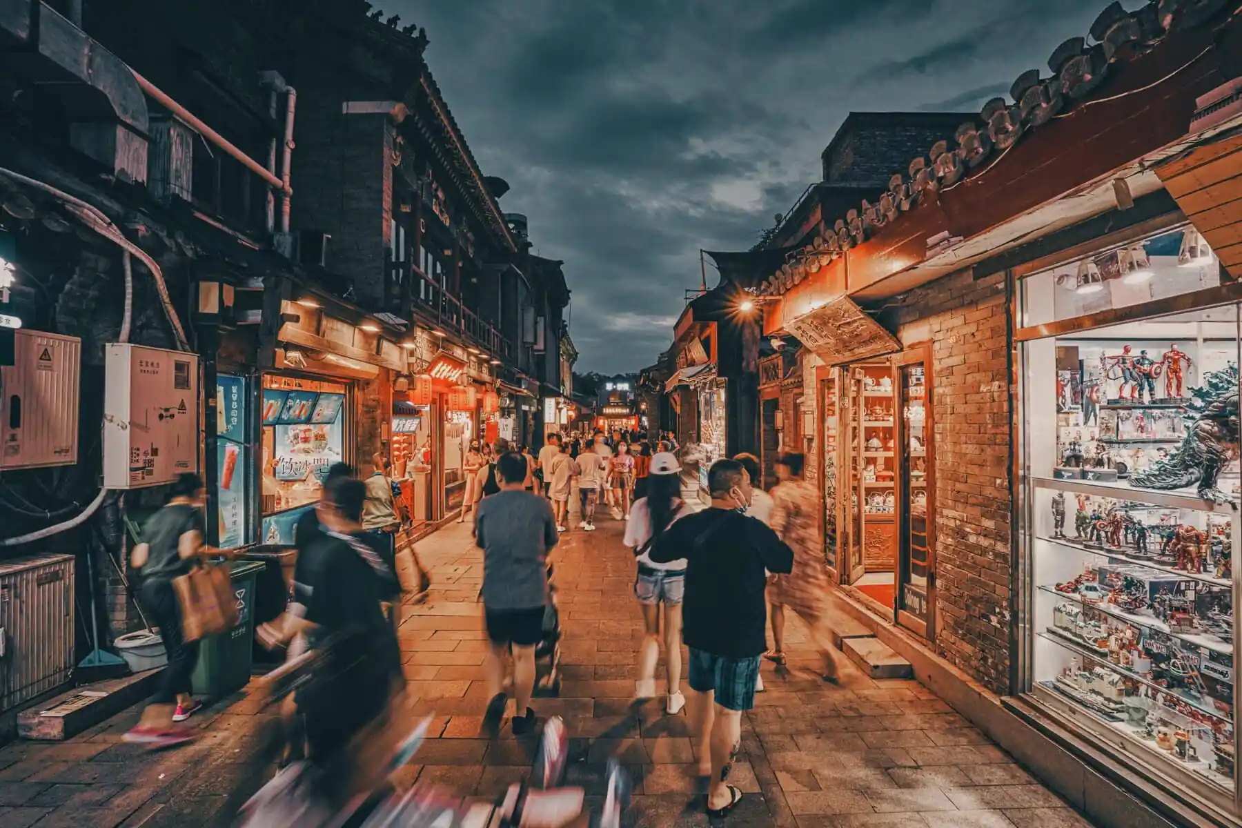 Bustling night market street lined with shops and Beijing hutong, chinatravel, illuminated displays, people walking and browsing.