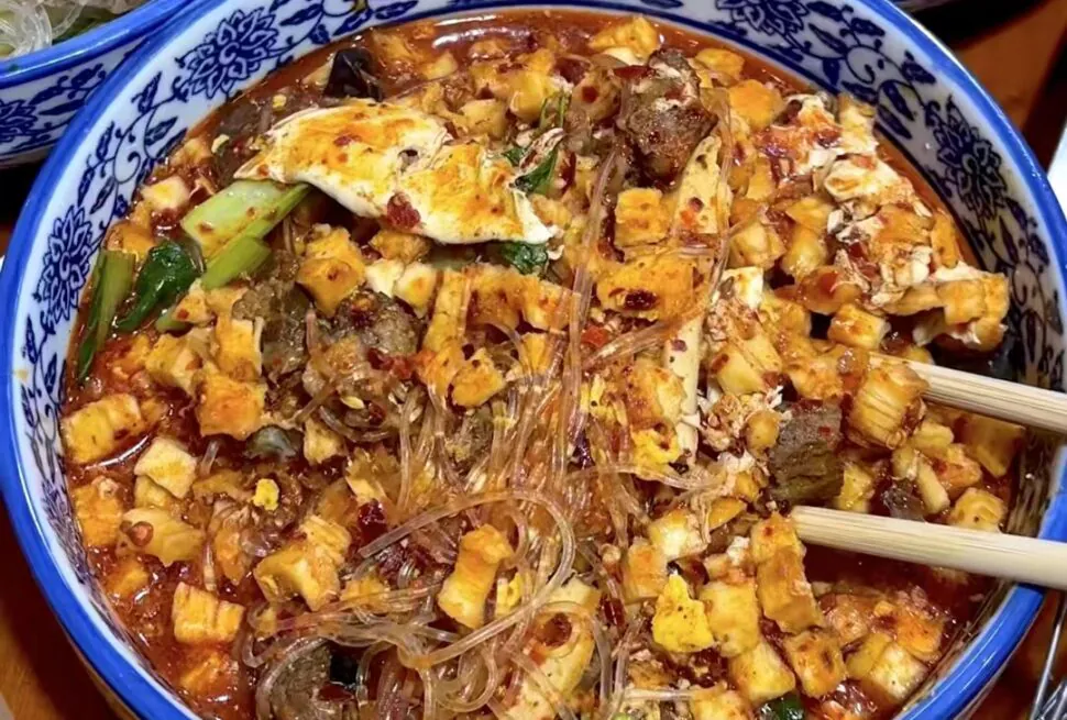 Xi'an Food, Stir Fried Bao Mo, china, chinaexplorertour, Blue patterned bowl of spicy tofu and glass noodle dish with chili oil, minced vegetables and greens; chopsticks rest on the side.