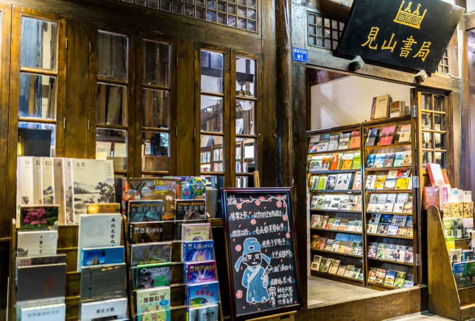 chengdu alley, The Ultimate Shopping Guide to China: What and Where to Buy, chinaexplorertour, Wood-framed bookstore storefront with large windows and shelves of colorful Chinese books outside the entrance.