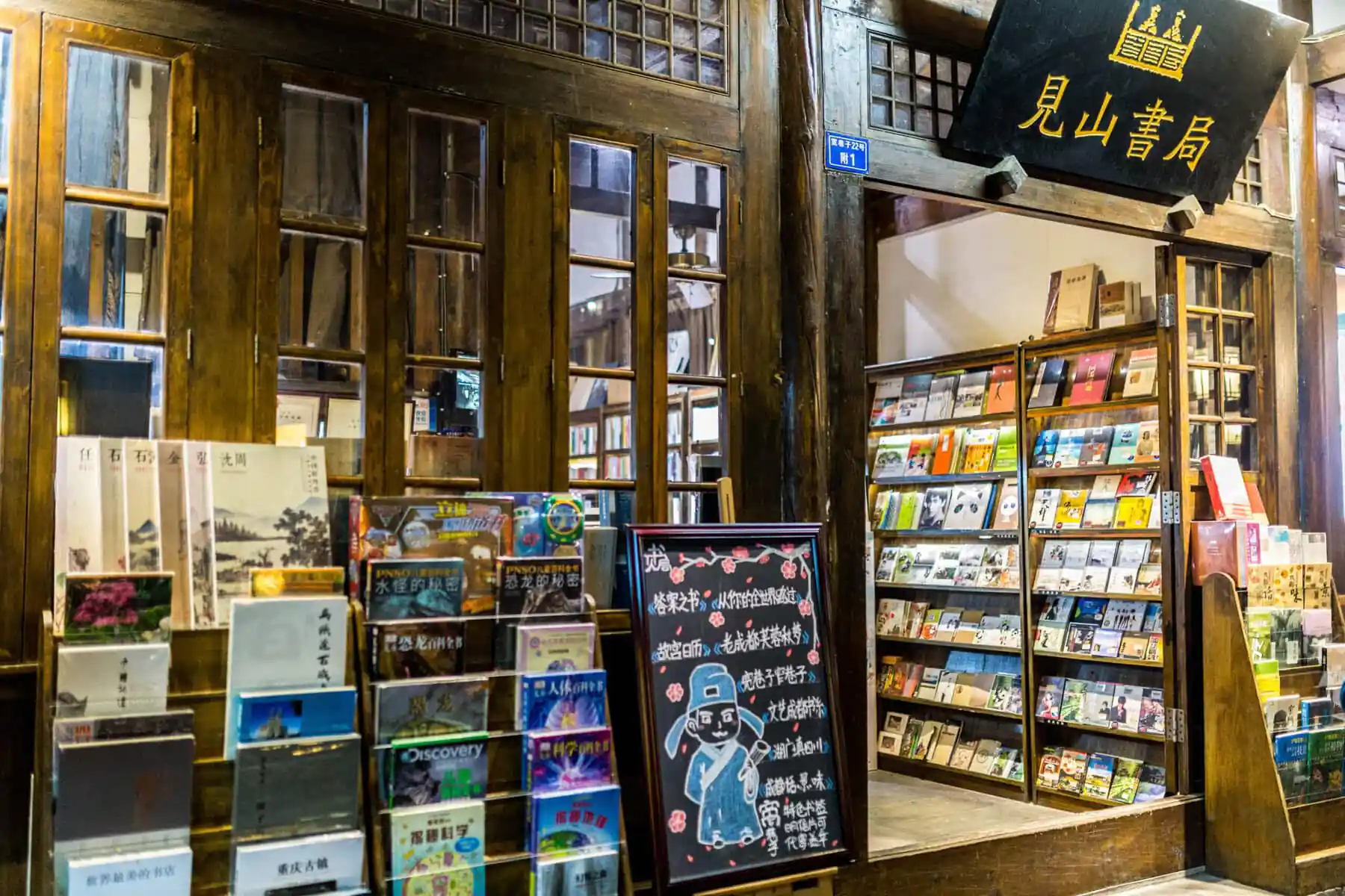 chengdu alley, The Ultimate Shopping Guide to China: What and Where to Buy, chinaexplorertour, Wood-framed bookstore storefront with large windows and shelves of colorful Chinese books outside the entrance.
