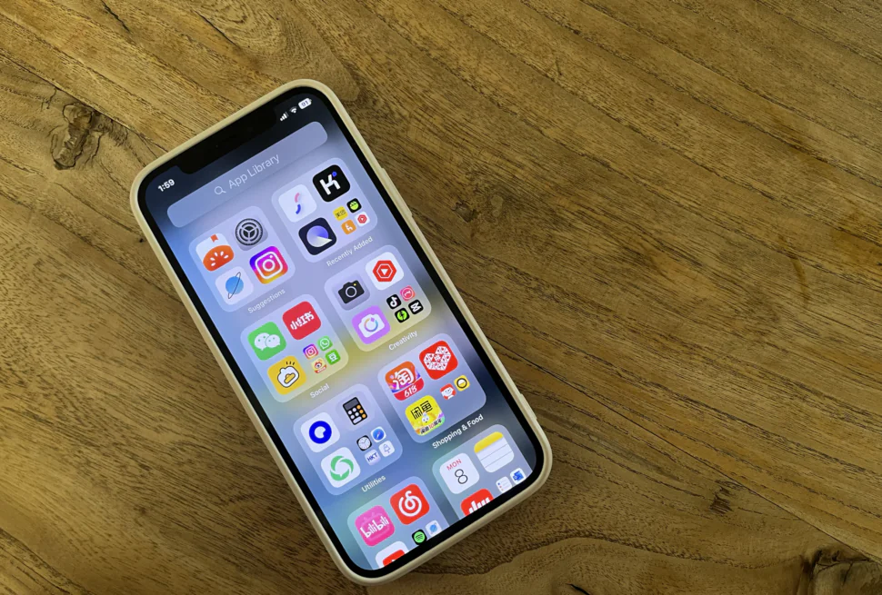How To Stay Connected In China 2025: Internet, VPN And SIM Cards, chinaexplorertour, Smartphone with a grid of colorful app icons on a wooden table surface, seen at an angle.