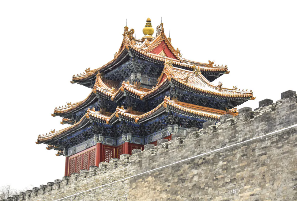 Ornate multi-tiered Chinese temple roof with gold accents and upturned eaves atop a stone wall.