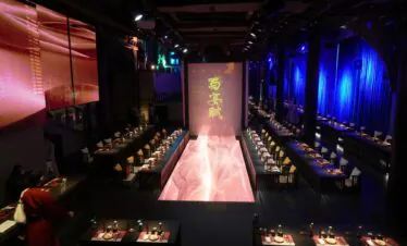 Sichuan Banquet Fu, sichuan, china, china tour, A fashion runway in a dark venue with pink-lit catwalk, seating along both sides, and a screen with gold Chinese characters at the end.